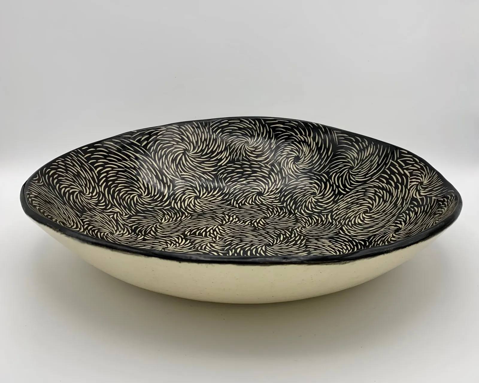 Sgraffito serving dish, 2024, glazed stoneware fired to Cone 6 oxidation, 3 x 12 x 12 in. A black serving dish with white carving in a floral pattern.
