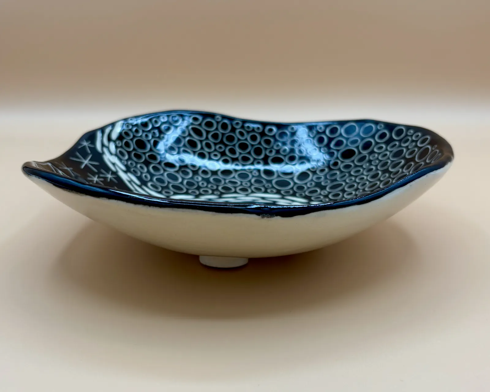 Sgraffito dish, 2026, glazed stoneware fired to Cone 6 oxidation, 2 x 7 x 7 in. A black dish with white carving in a variety of patterns.