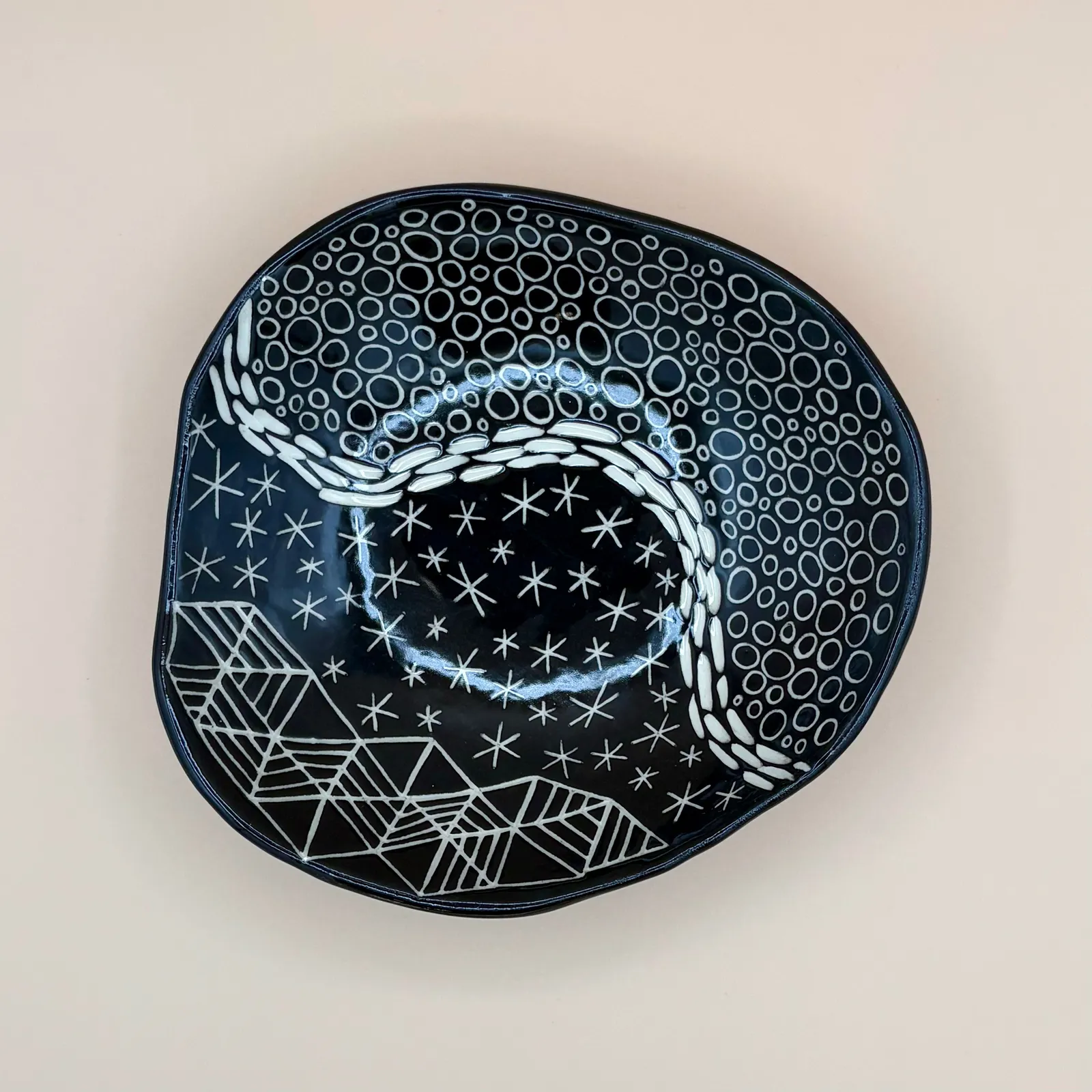 Sgraffito dish, 2026, glazed stoneware fired to Cone 6 oxidation, 2 x 7 x 7 in. A black dish with white carving in a variety of patterns.