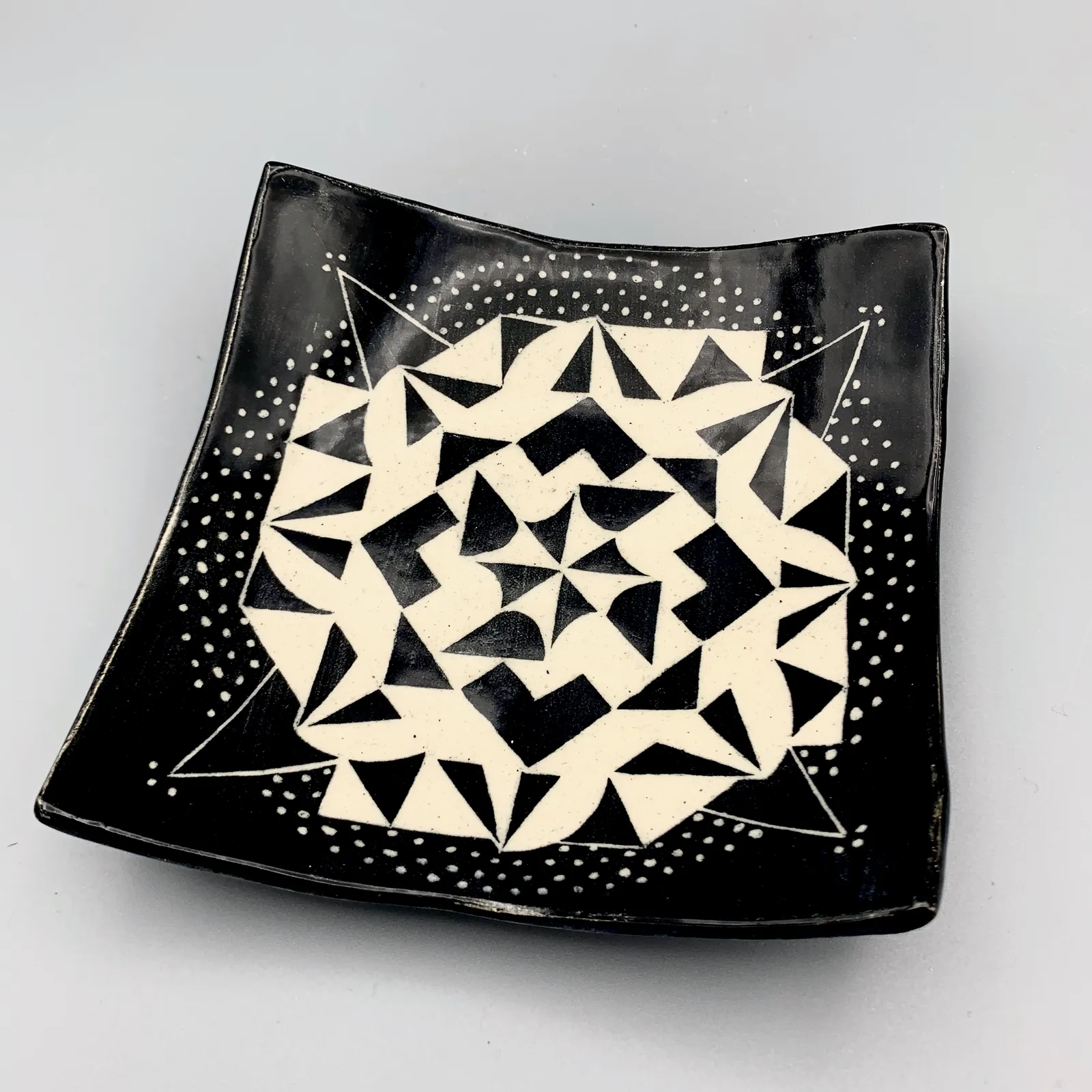 Sgraffito dish, 2021, glazed stoneware fired to Cone 6 oxidation, approx. 1 x 6 x 6 in. A black and white dish carved in a geometric pattern.