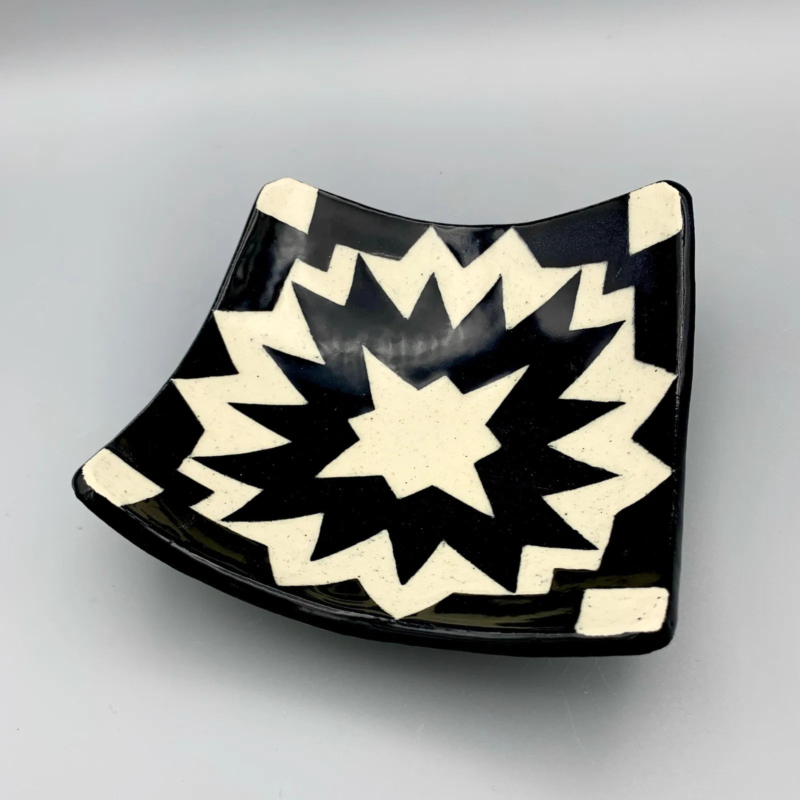 Sgraffito dish, 2021, glazed stoneware fired to Cone 6 oxidation, approx. 1 x 6 x 6 in. A black and white dish carved in a geometric pattern.