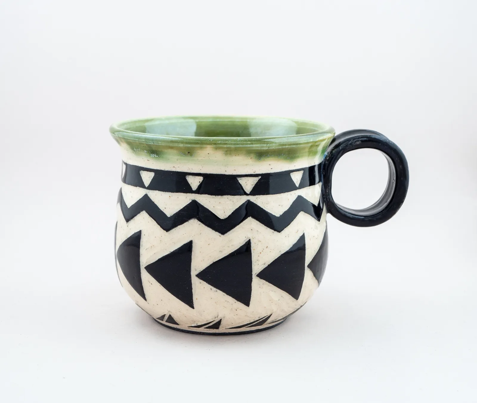 Sgraffito mug, 2019, glazed stoneware fired to Cone 6 oxidation, 3 x 5 x 4 in. A black and white mug carved in a geometric pattern.