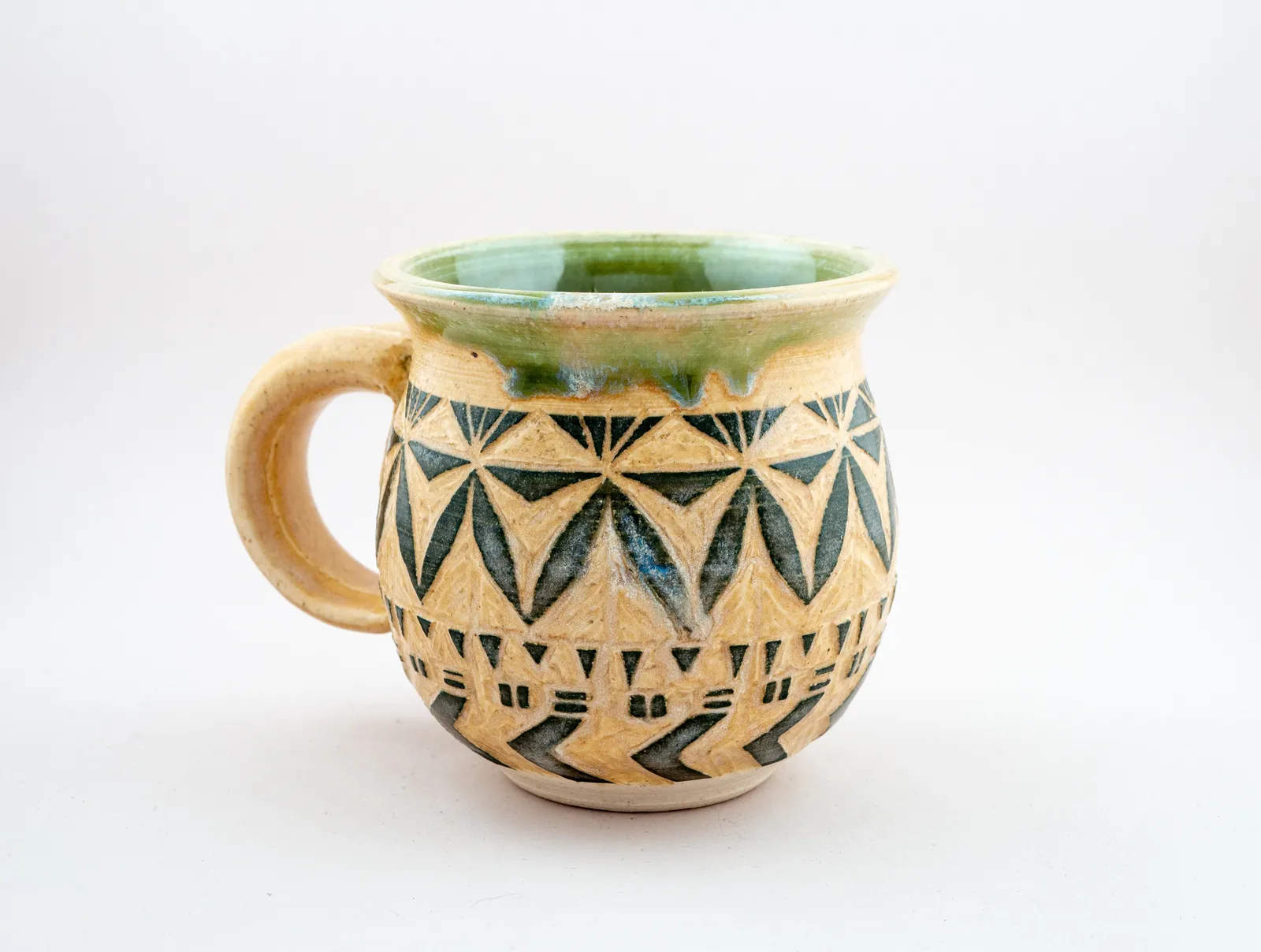 Sgraffito mug, 2019, glazed stoneware fired to Cone 6 oxidation, approx. 4 x 5 x 4 in. A green and honey-colored mug carved in a geometric pattern.